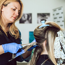 Coiffeuse appliquant une coloration blonde au Salon Maël Coiffure à Strasbourg.