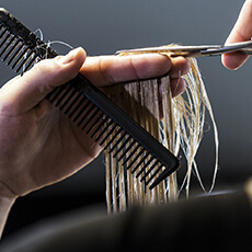 Coiffeur coupant les cheveux mouillés avec précision dans le salon Maël Coiffure à Strasbourg.